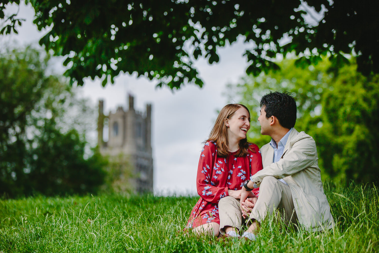 Engaged couple in Ely, photographed by Ely Photographer. Couple sitting on grass near Ely Cathedral.
