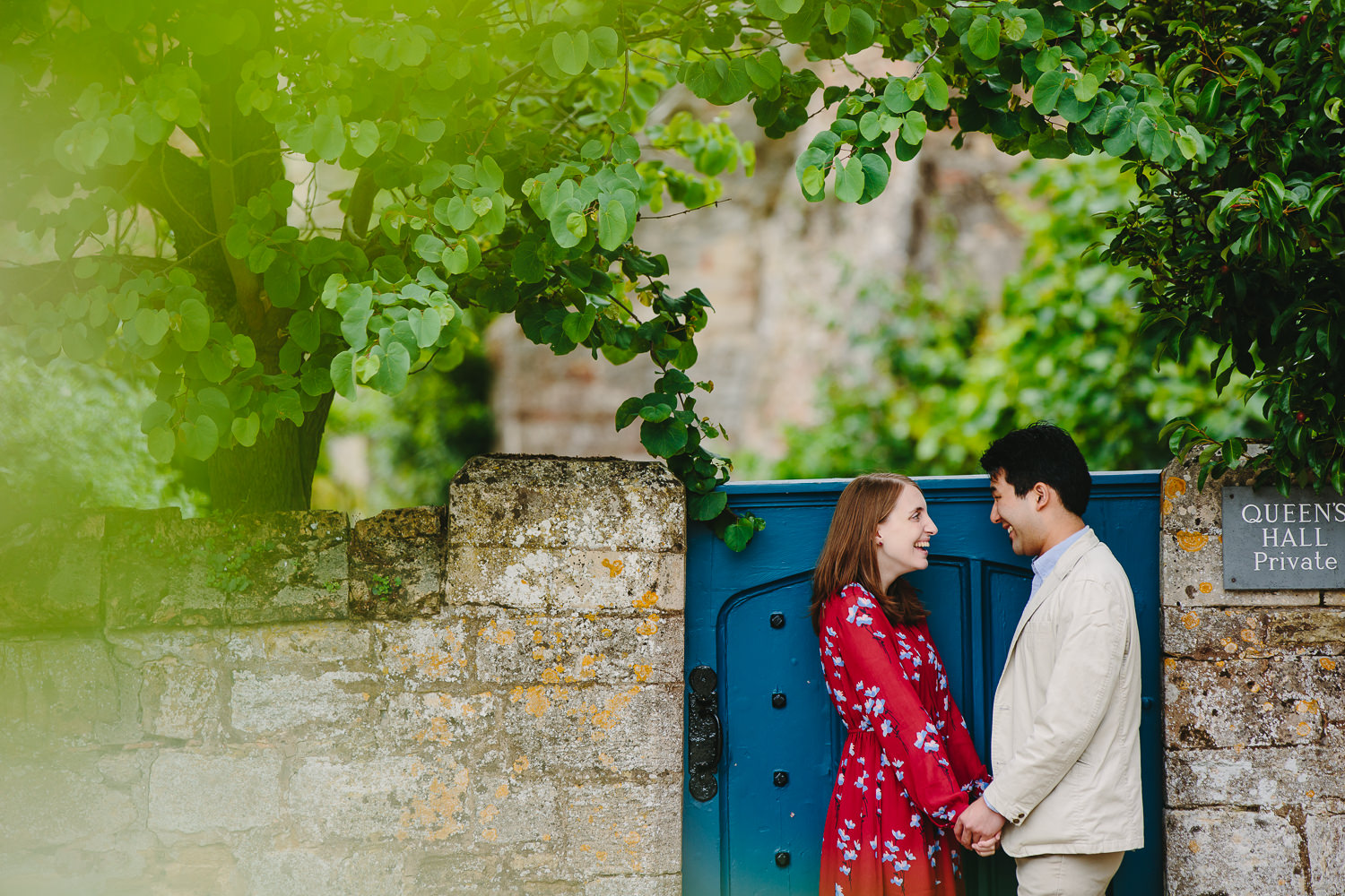 Engaged couple in Ely, photographed by Ely Photographer. Couple standing by a stone wall and blue gate.