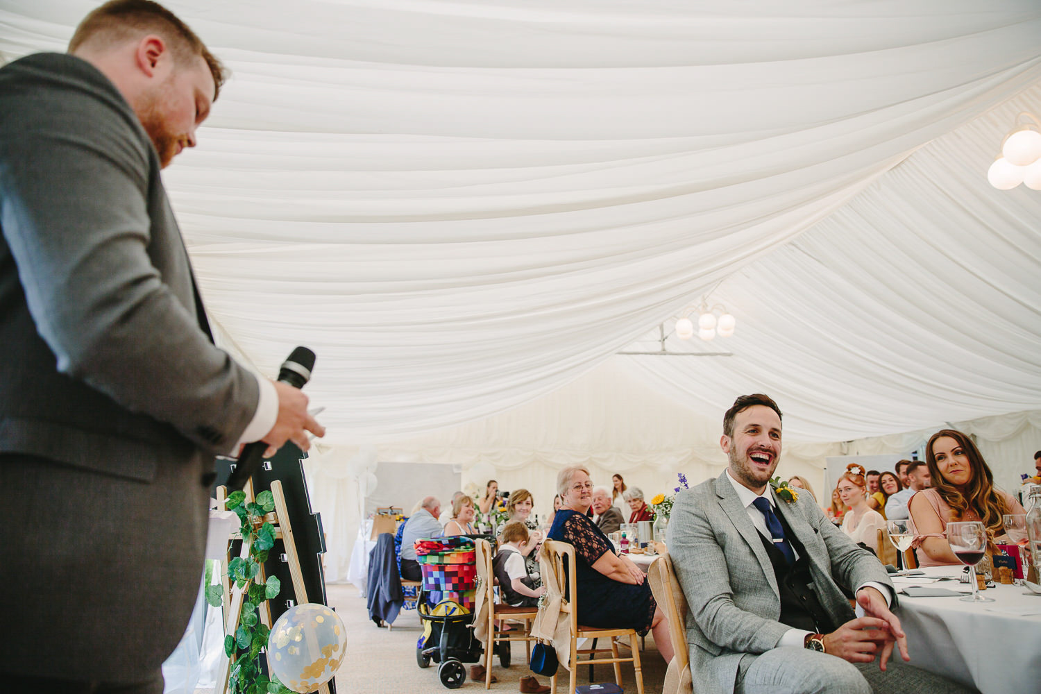 Best man wedding speech, groom laughing, wedding guests