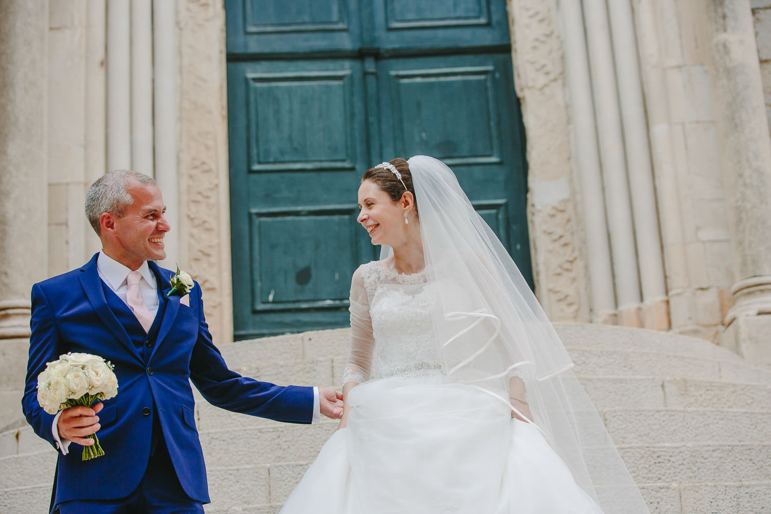 Bride and groom in front of green door, walking down steps