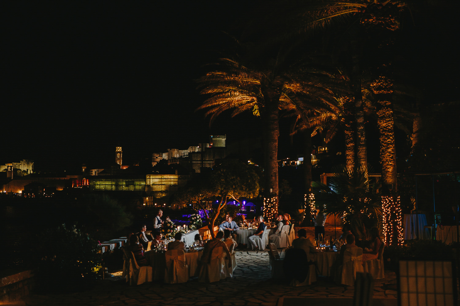 Night time, wedding reception, wedding tables, wedding guests, palm trees, the sea