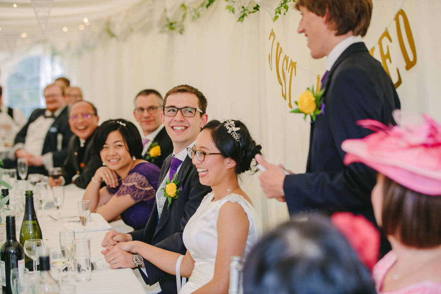 Bride and groom laughing with wedding guests, wedding top table.