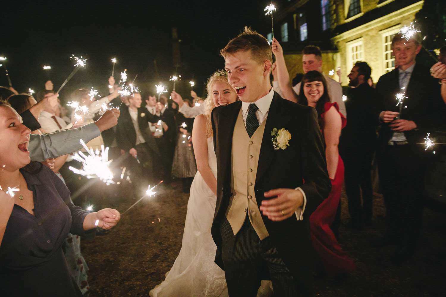 Bride and groom walk through a crowd of people holding sparklers