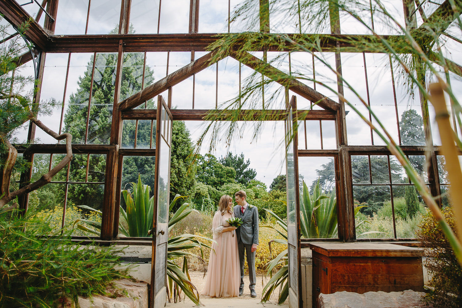 Bride and groom portrait in a green house.