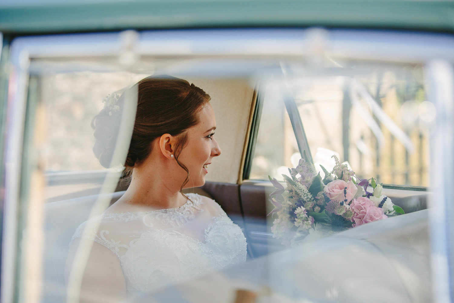 Bride in wedding car, looking out of the window.