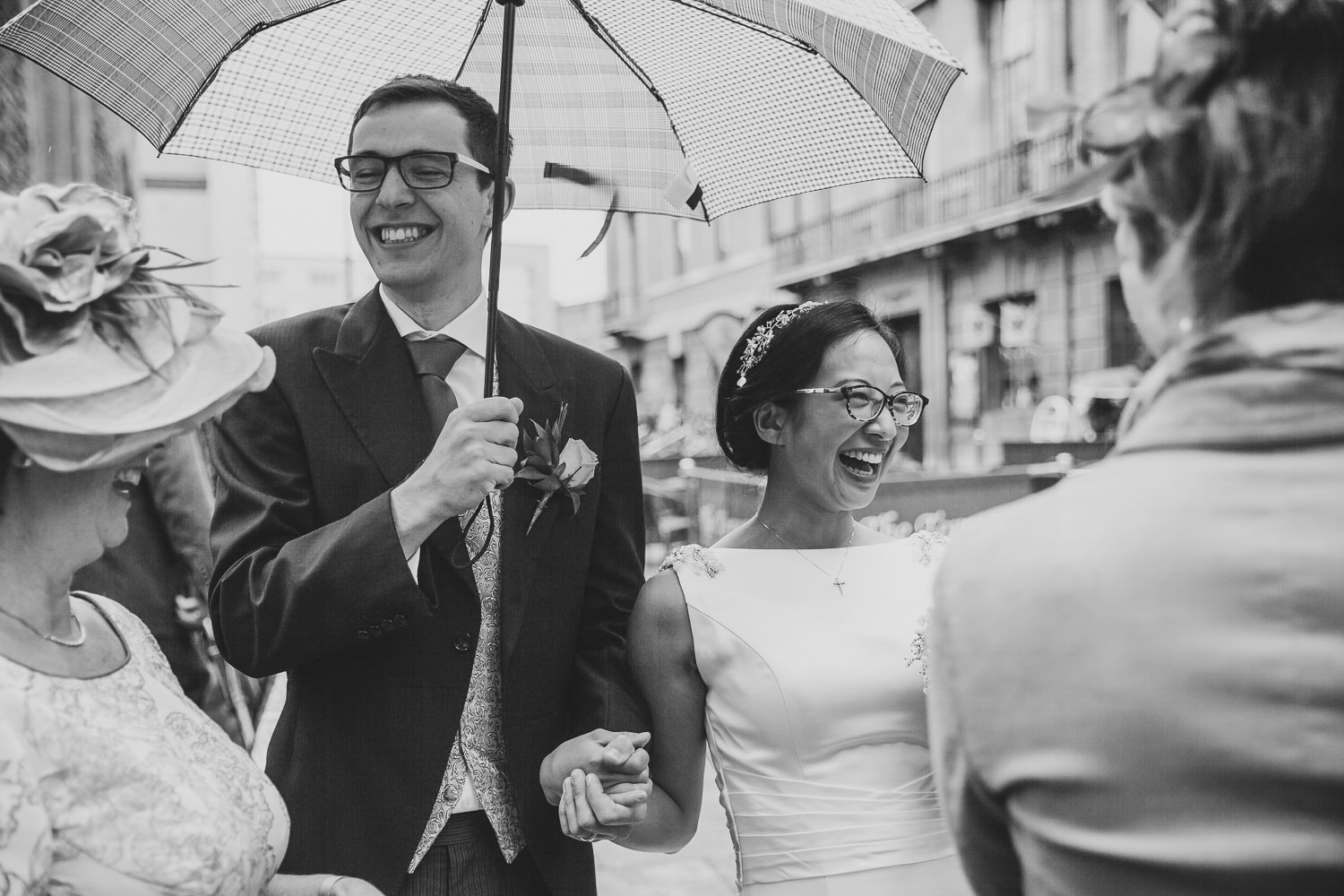 Bride and groom smiling with umbrella