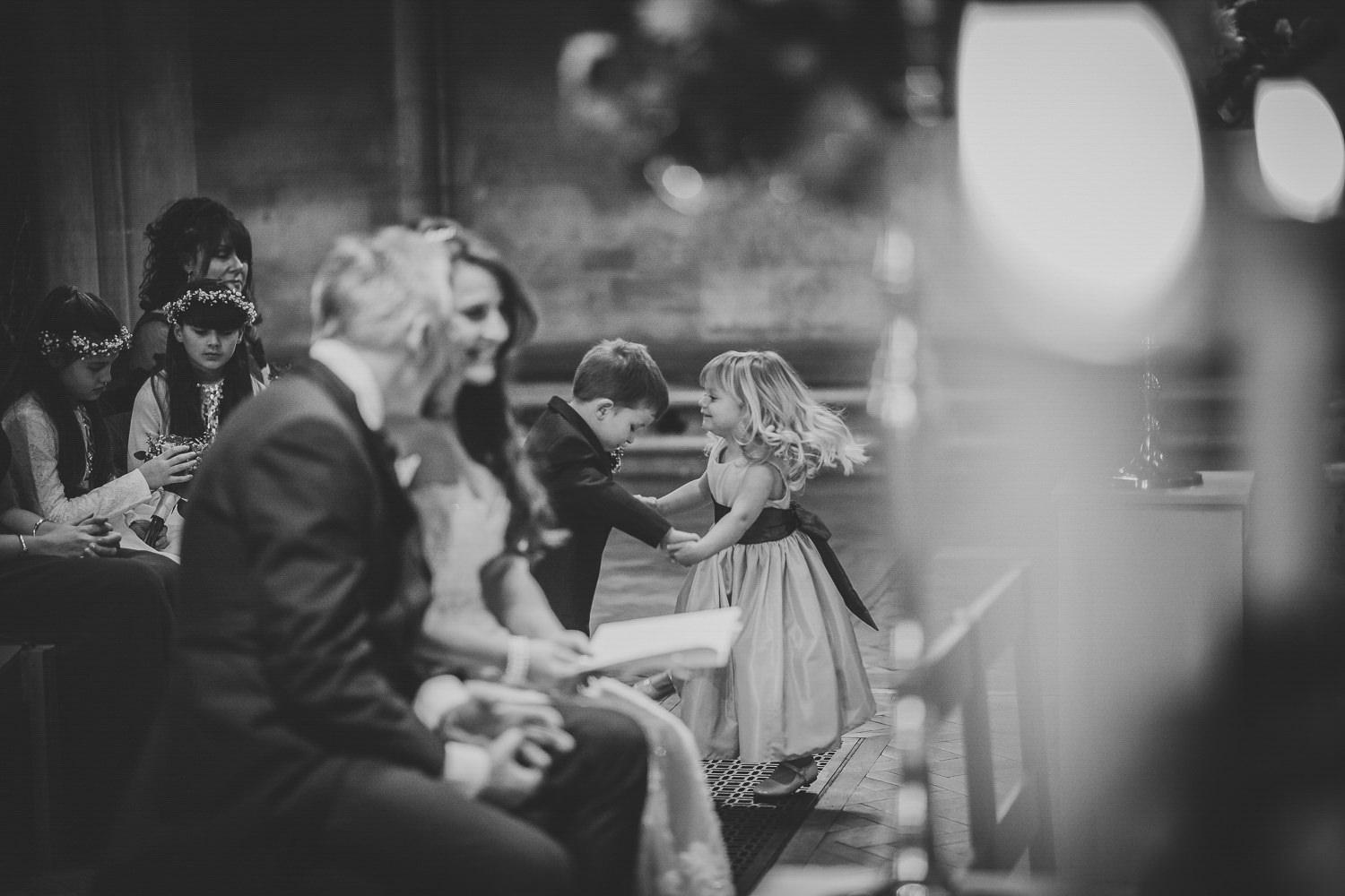 Bride and groom in church, page boy and flower girl dancing in the back ground