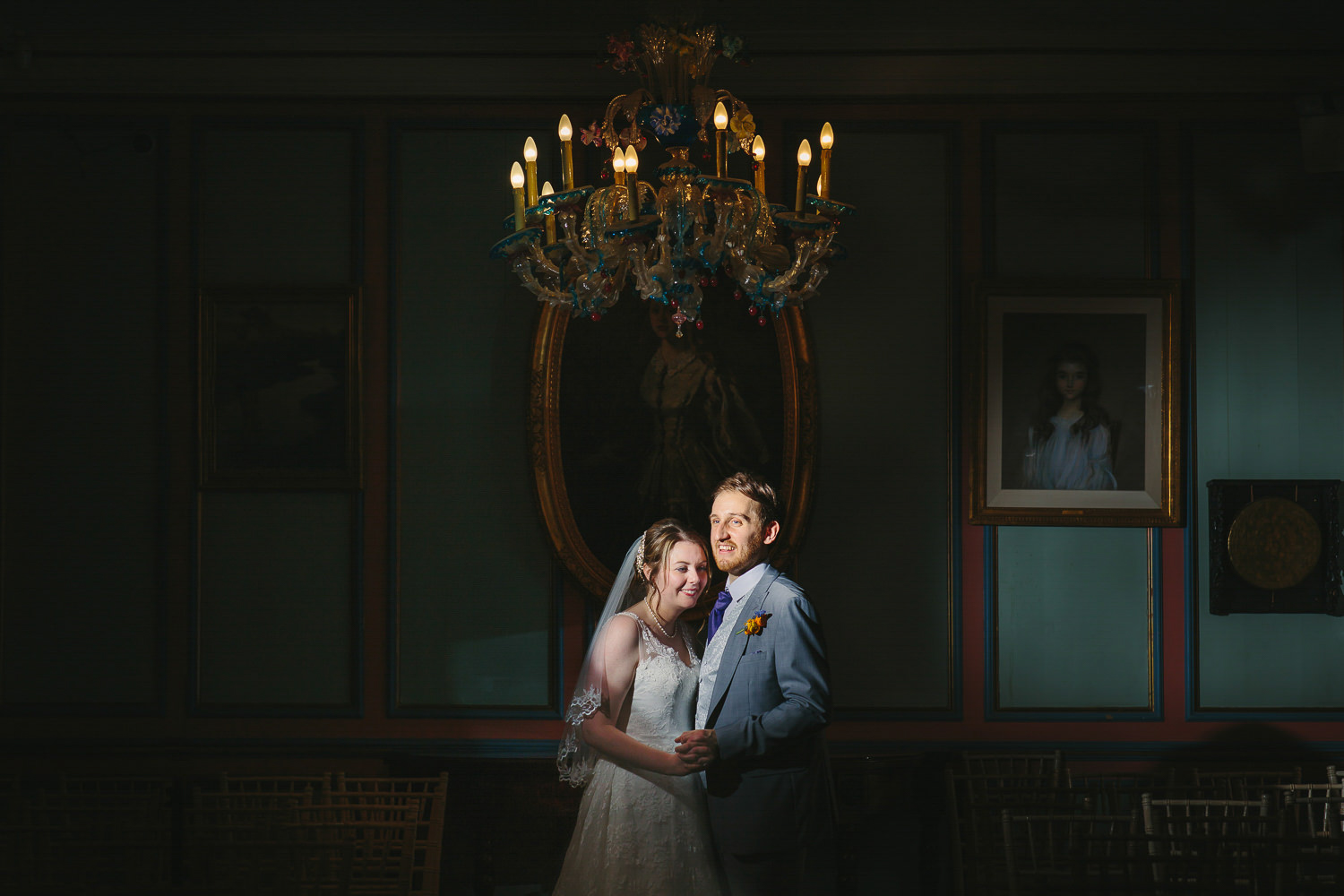 Bride and groom indoor portrait. Green walls, paintings and chanderlier