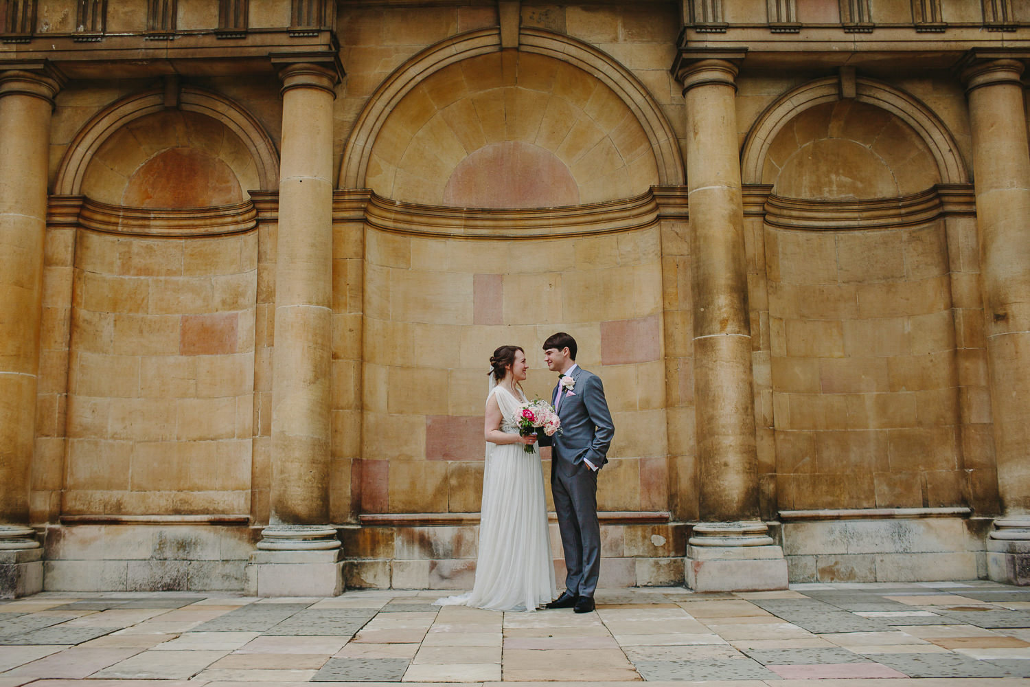 Bride and groom in front of stone architecture