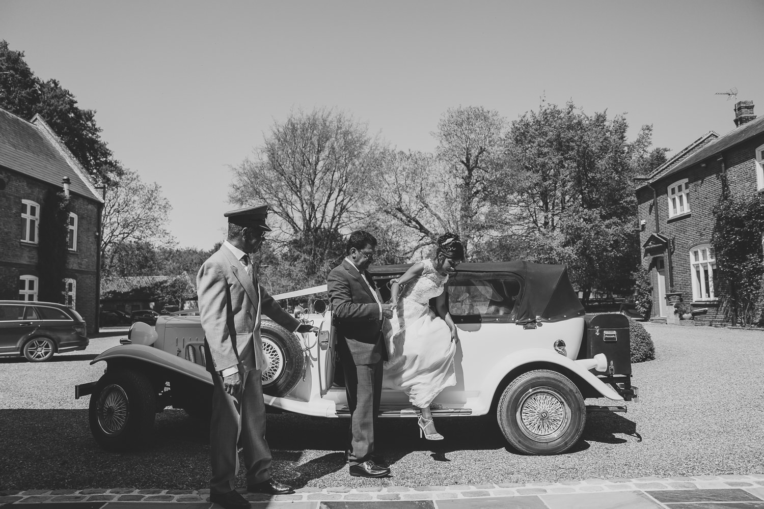 Bride, father and chauffer arriving by classic car
