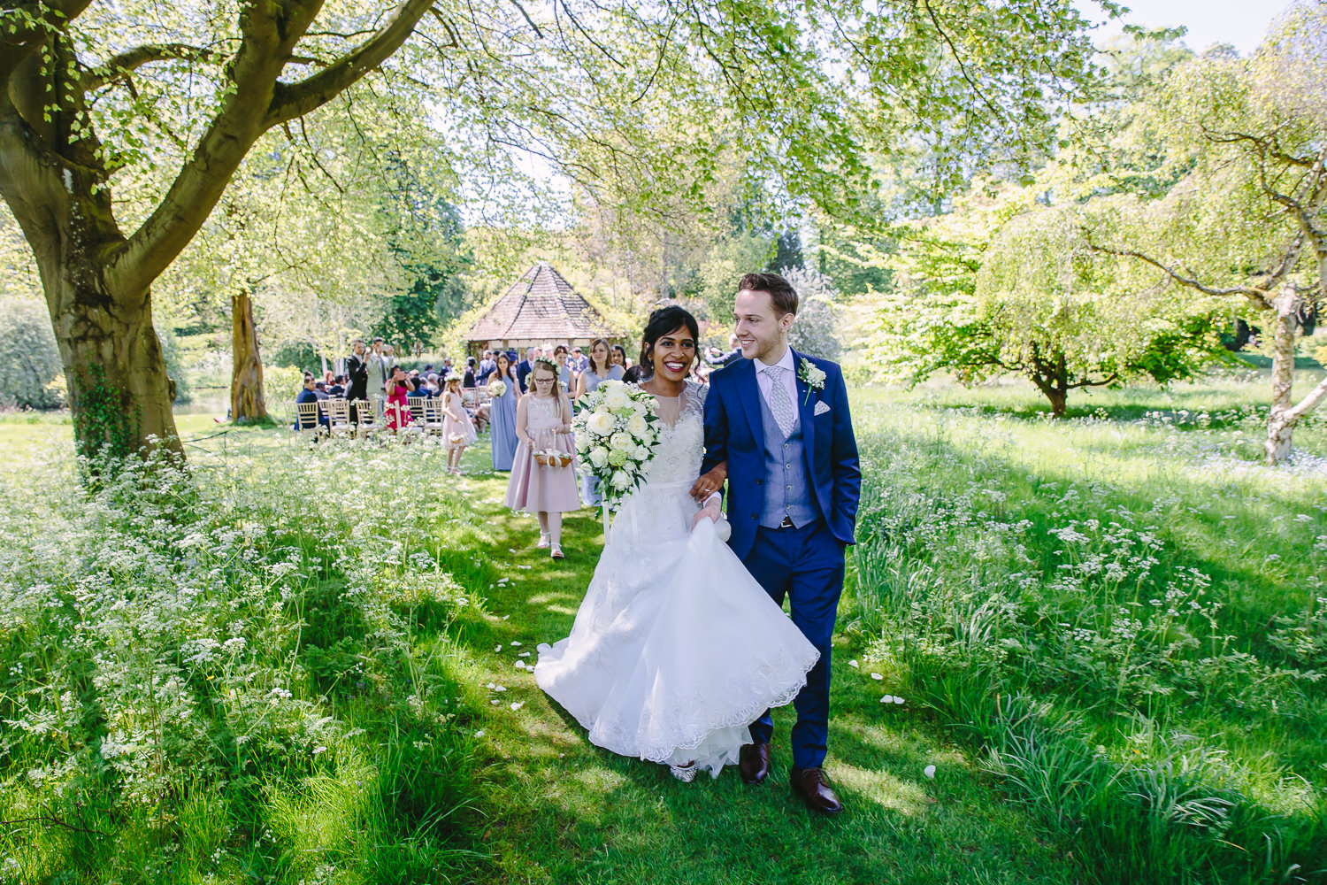 Bride and groom walking through a meadow in summer