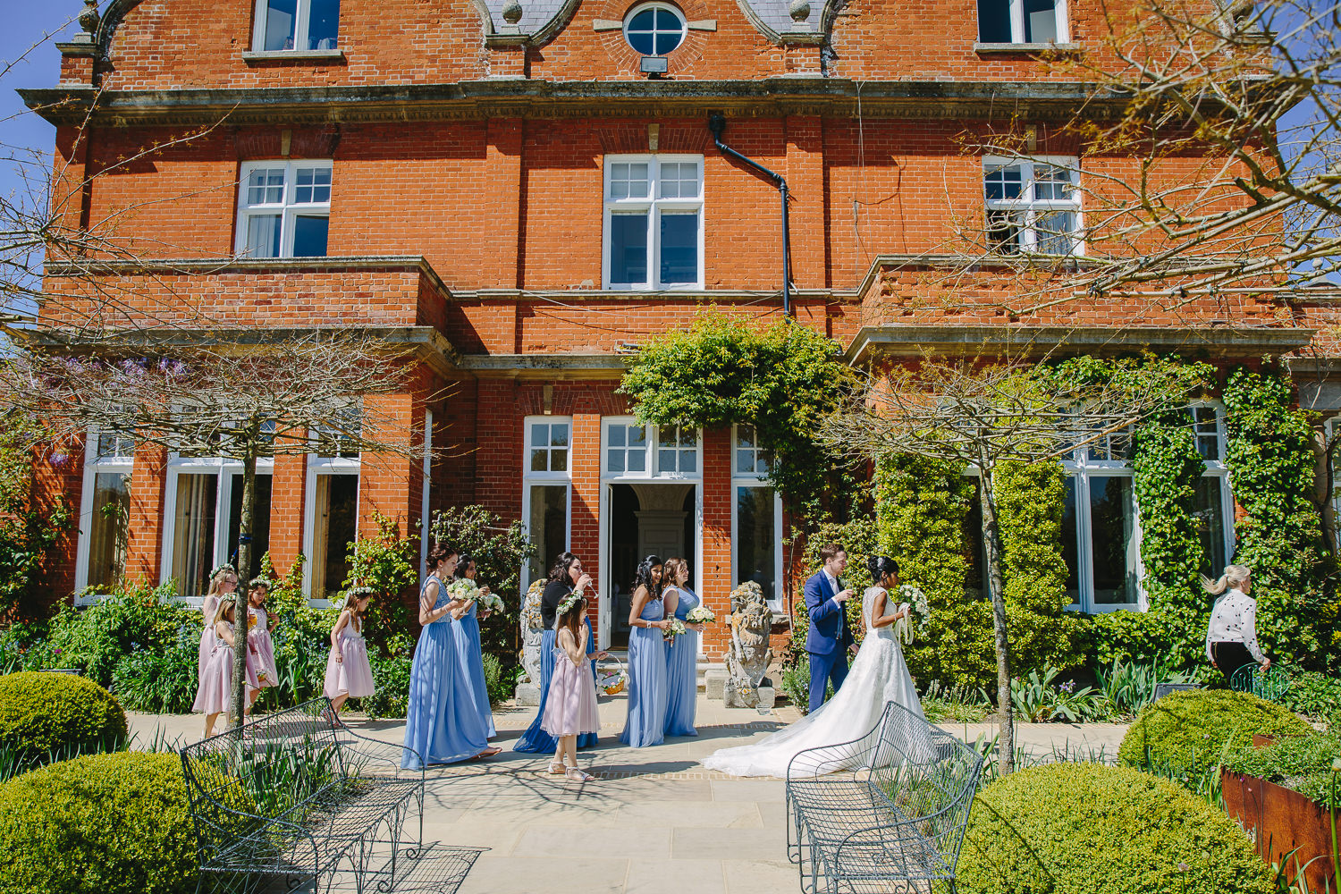 Bride, groom and bridesmaids walking in front of Chippenham Park House