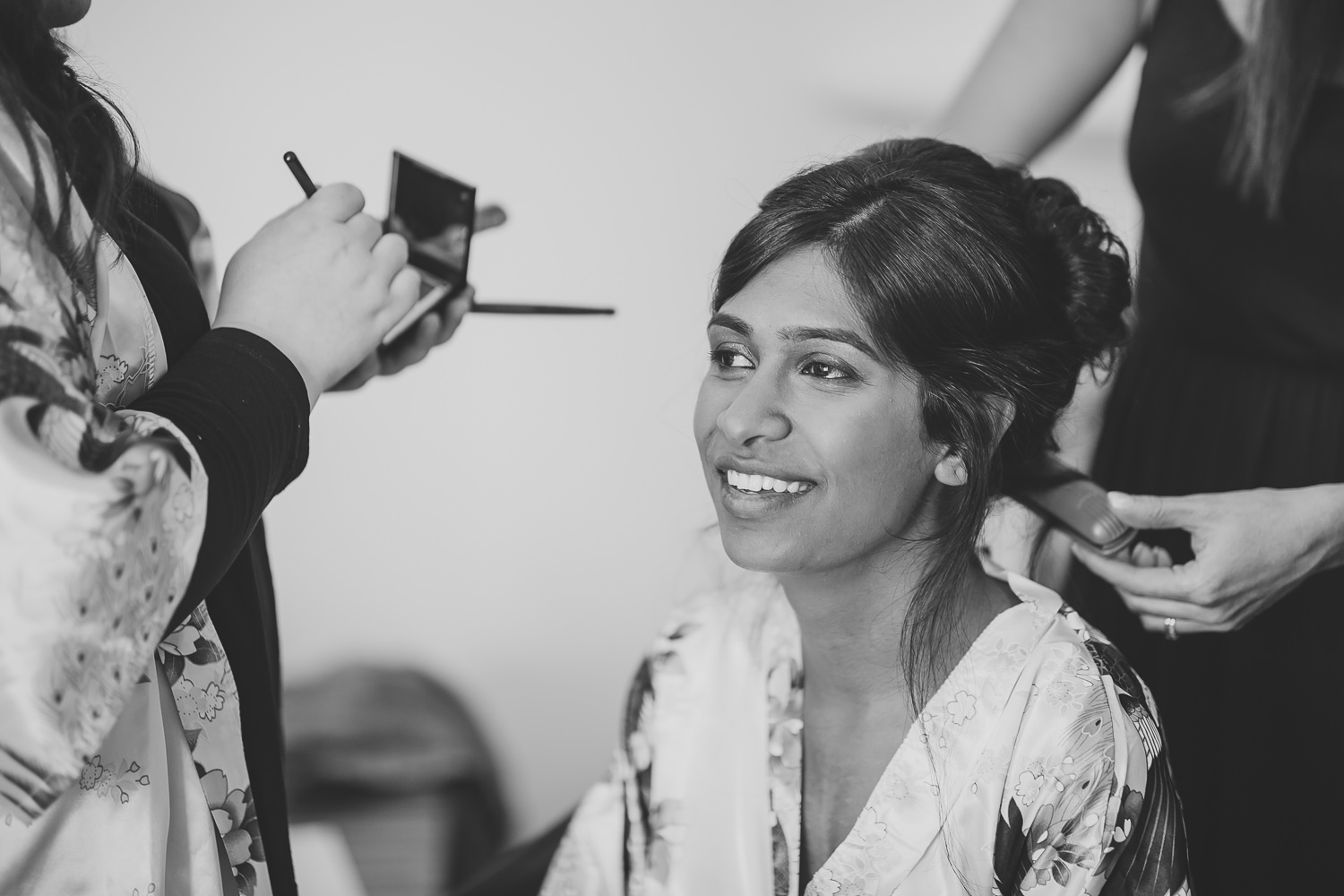 Bride smiling while having makeup applied