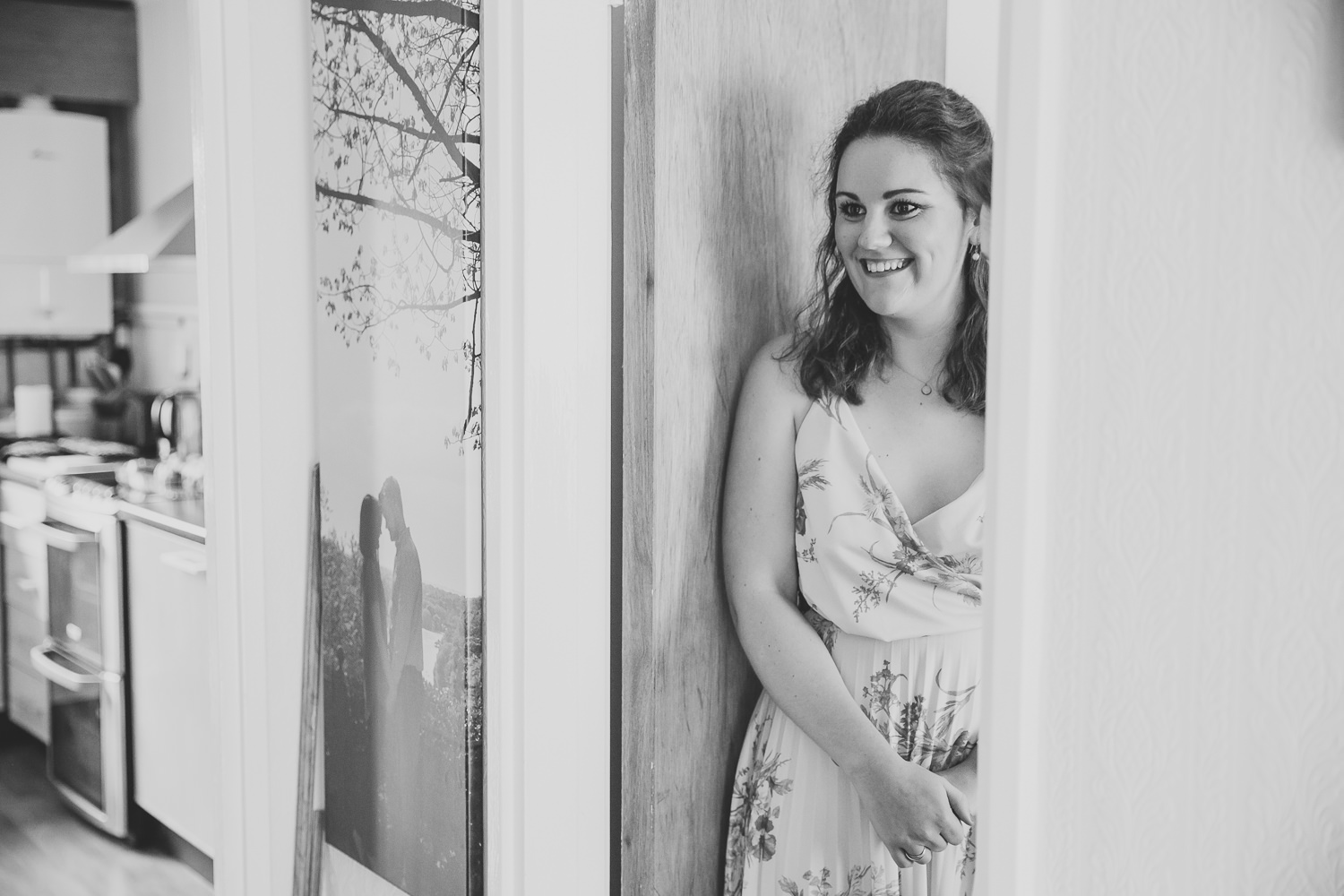 Black and white photo of girl standing in a door in a house, smiling