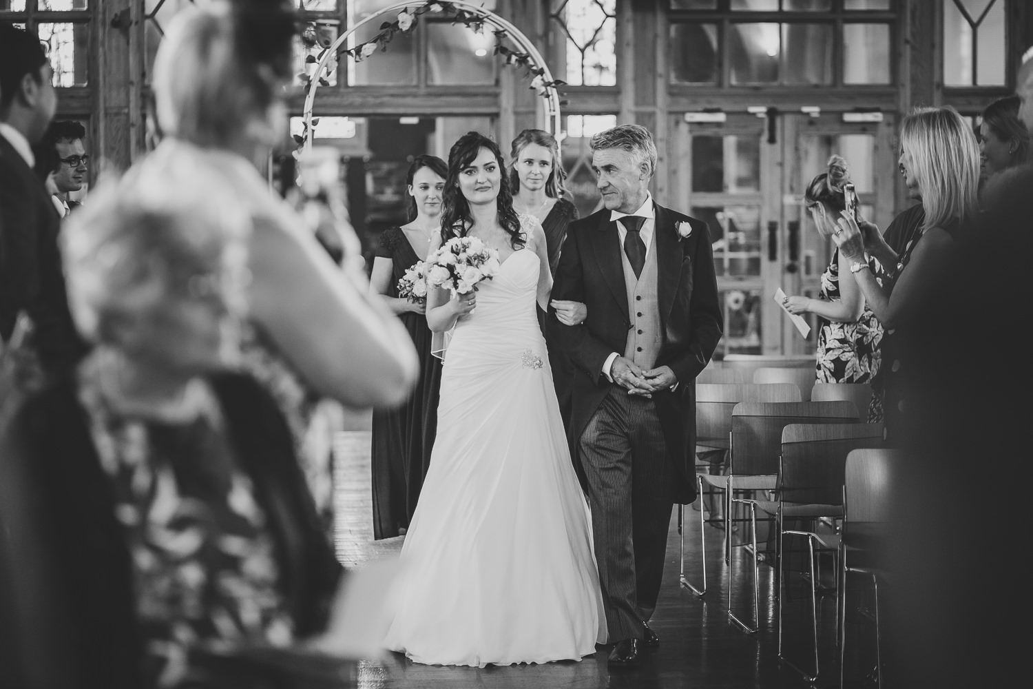 Black and white photo of bride and father walking down the aisle