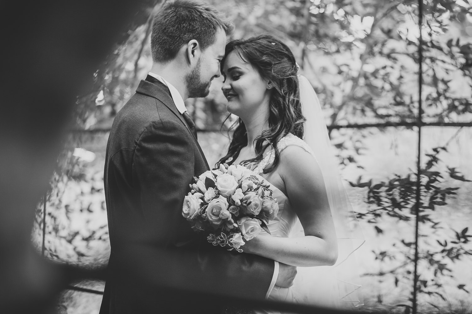 Black and white wedding photography of bride and groom in the park.