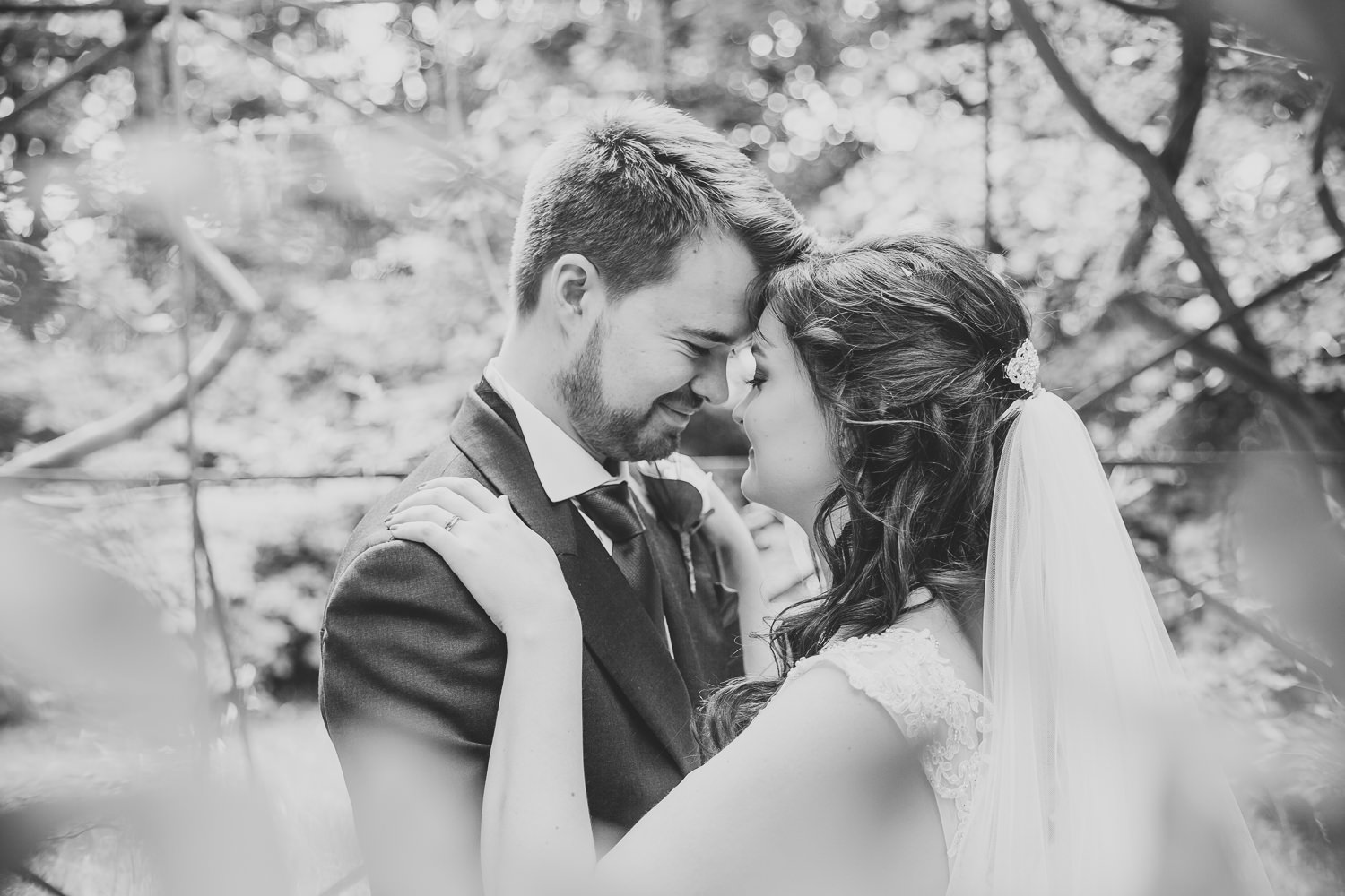 Black and white wedding photography of bride and groom in the park.