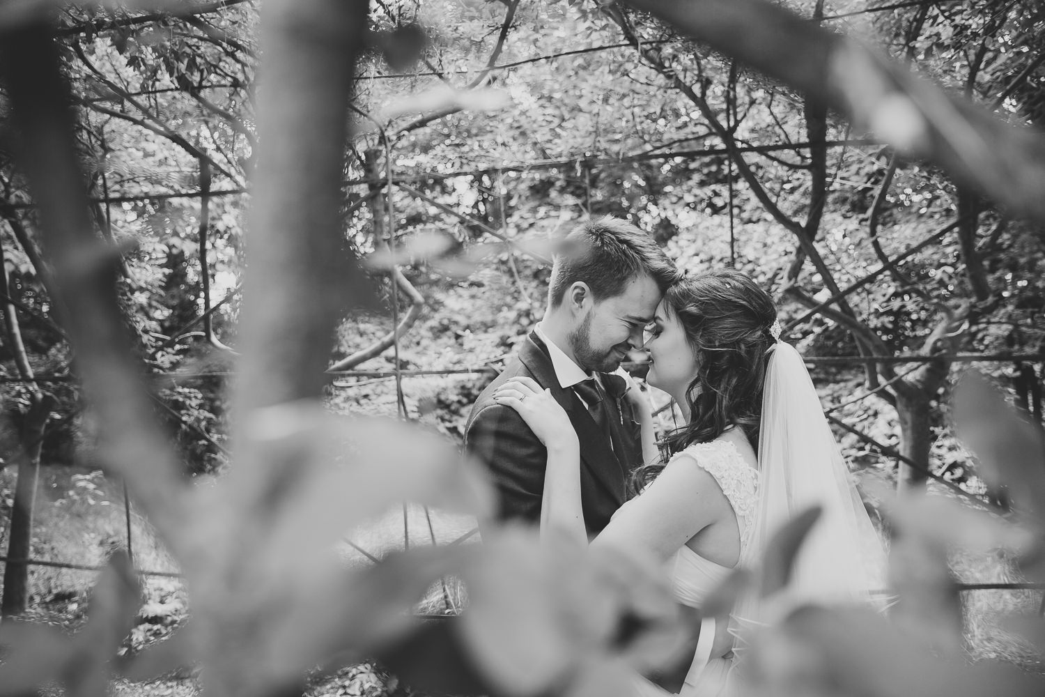 Black and white wedding photography of bride and groom in the park.