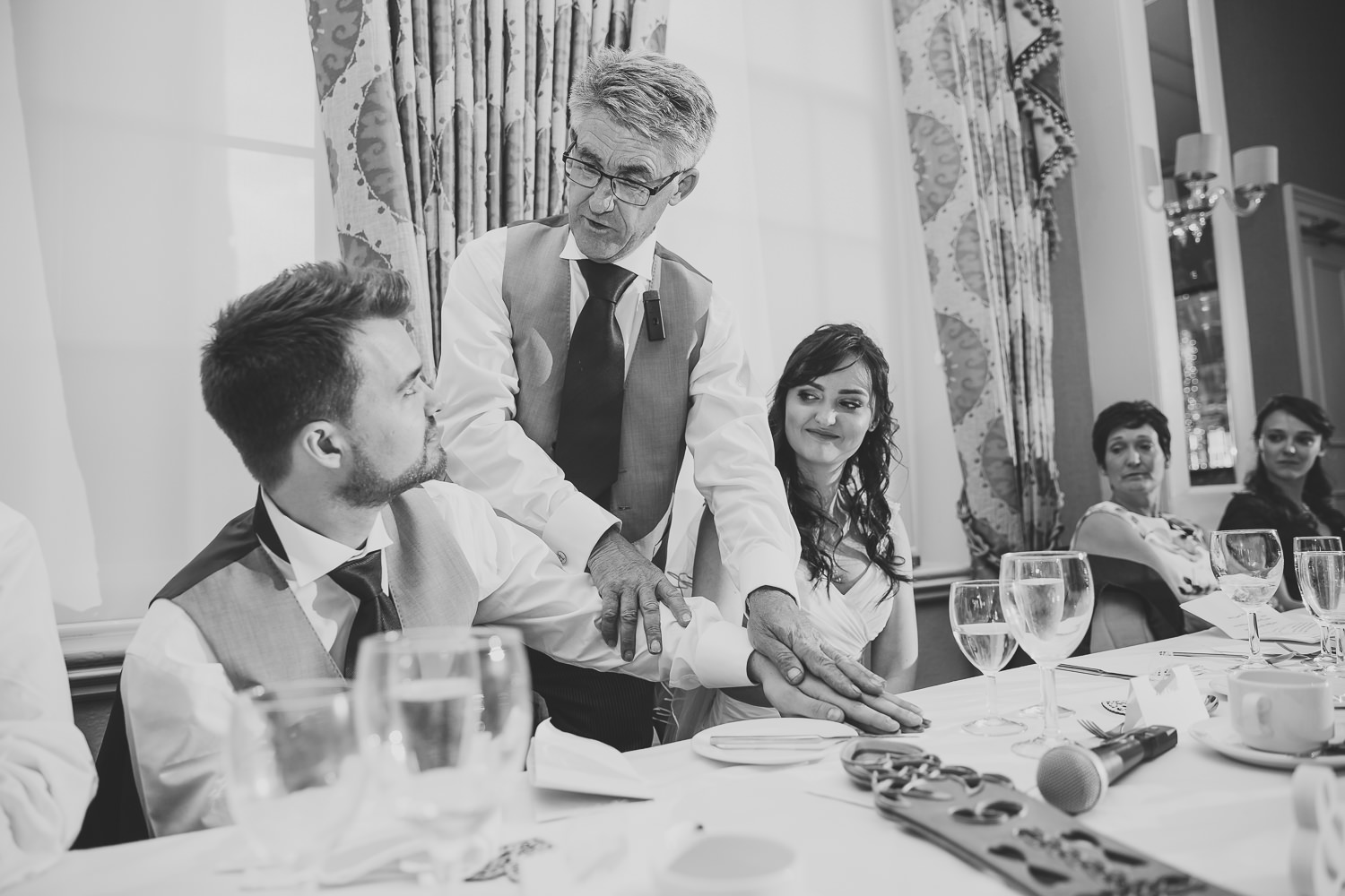 Black and white wedding photography of bride and groom during wedding speeches at top table a Richmond Hill Hotel, London