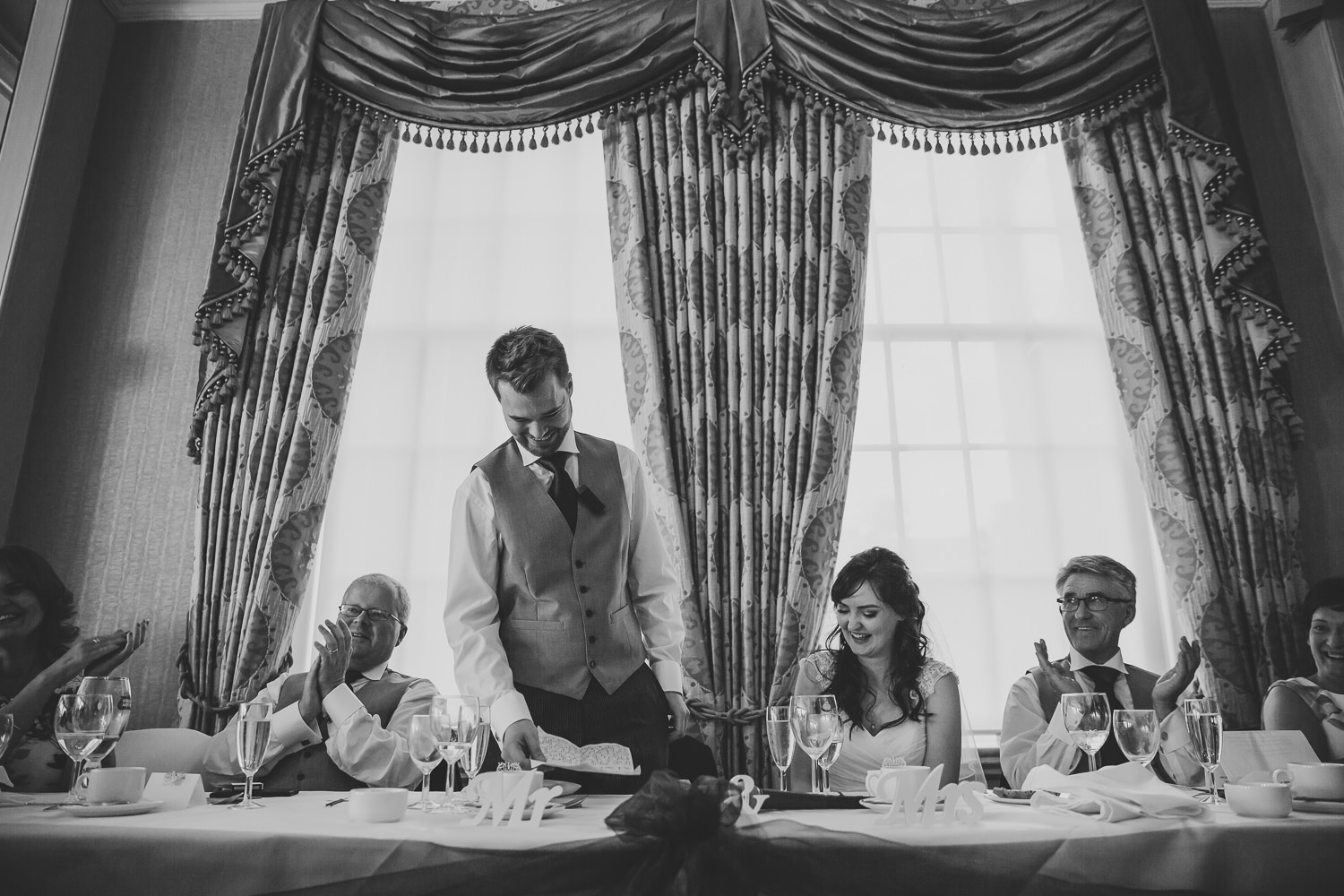 Black and white wedding photo of bride and groom during wedding speeches at top table a Richmond Hill Hotel, London
