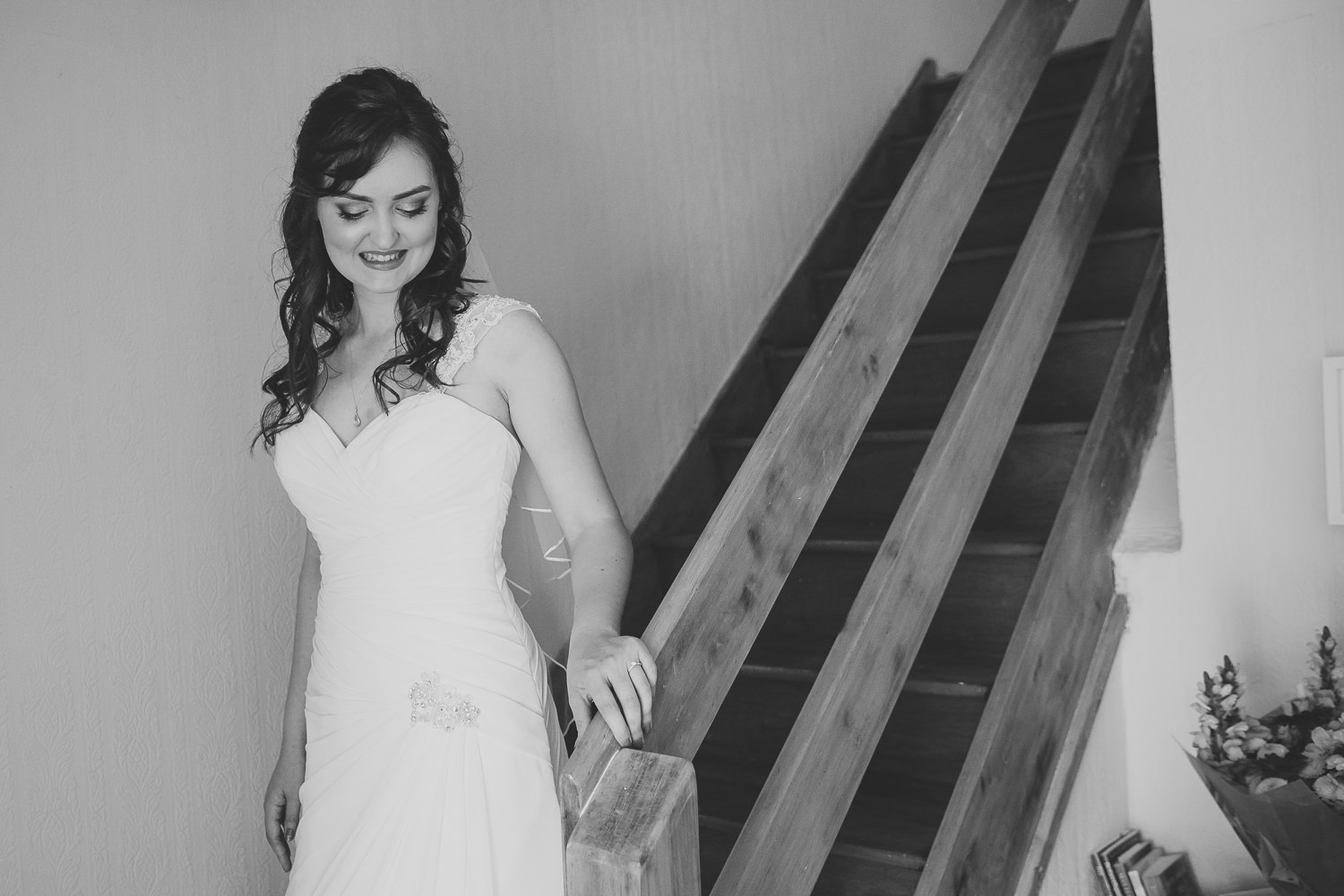 Black and white photo of bride walking down the stairs in modern house