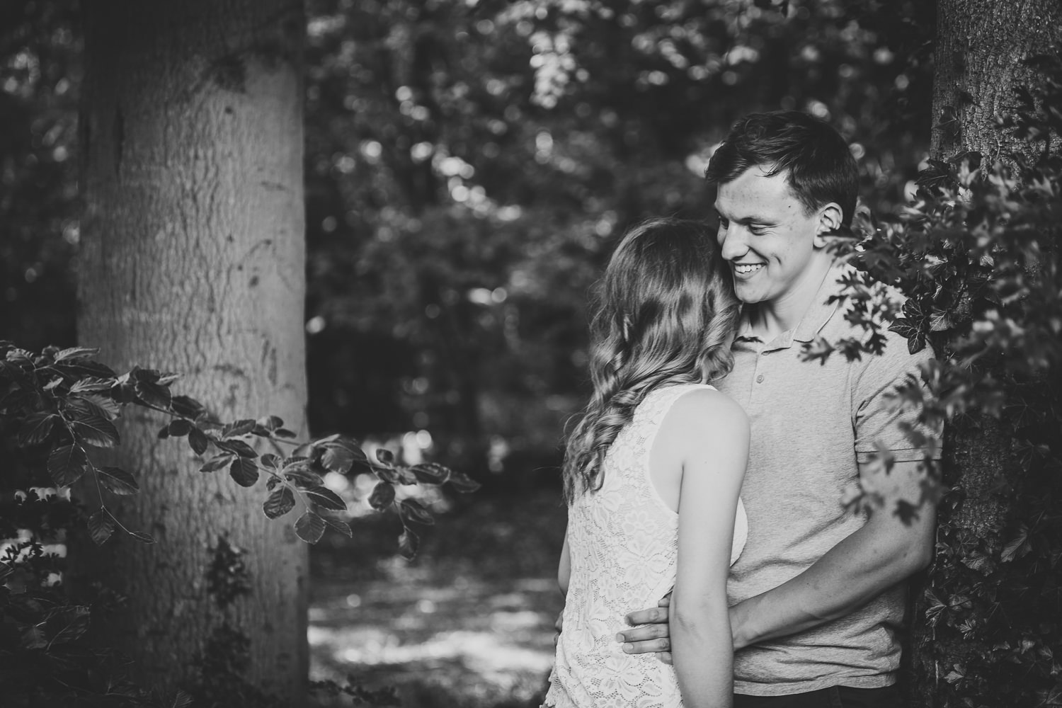 Black and White Photo captured by a Cambridge photographer, of an engaged couple in the woods.