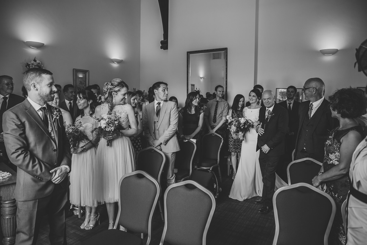 Bride walking down the aisle at Ely Registry office, being greeted by wedding guests and the groom. photographed by an Ely Wedding Photographer