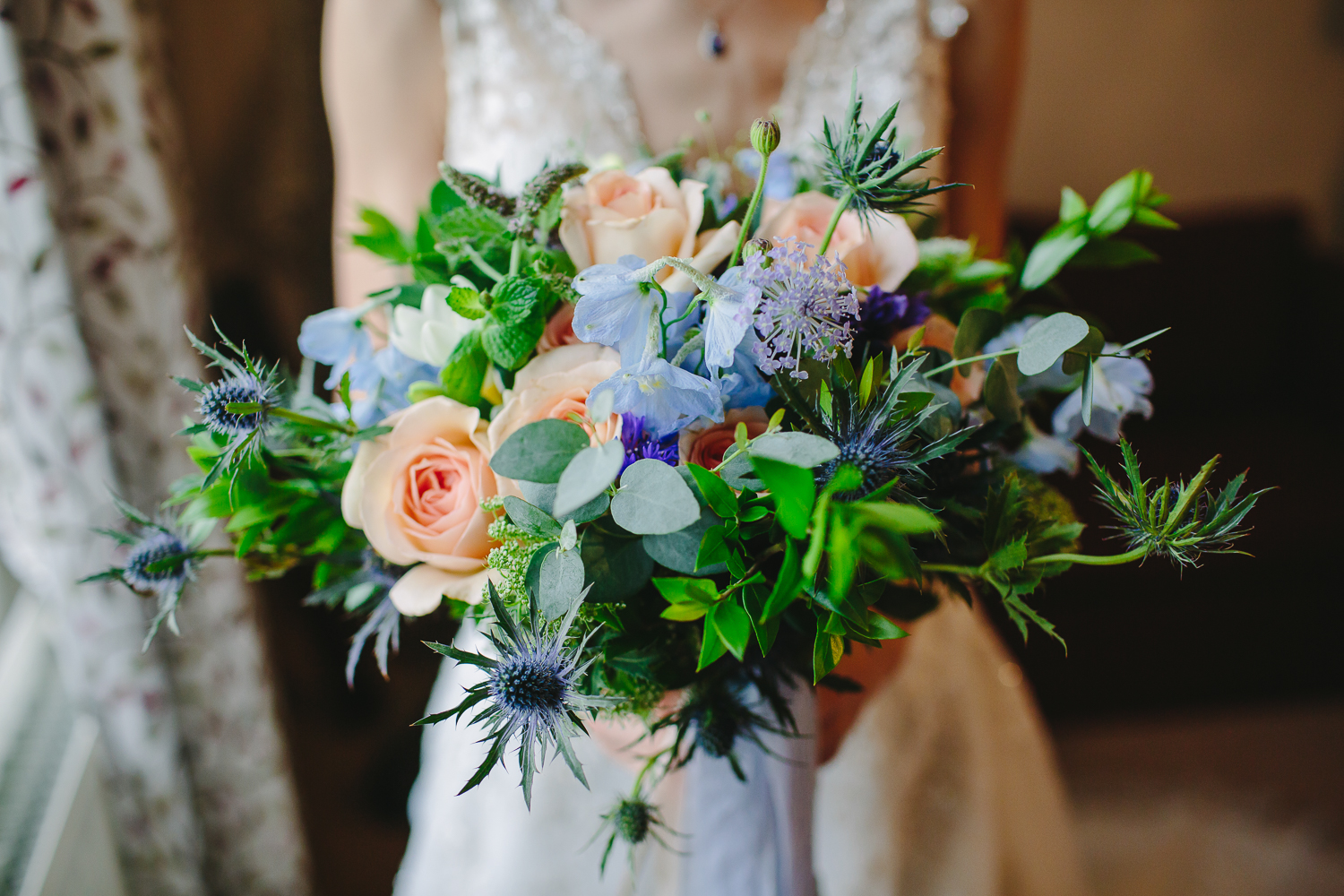 Bridal bouquet of blue and peach flowers, with green foliage.