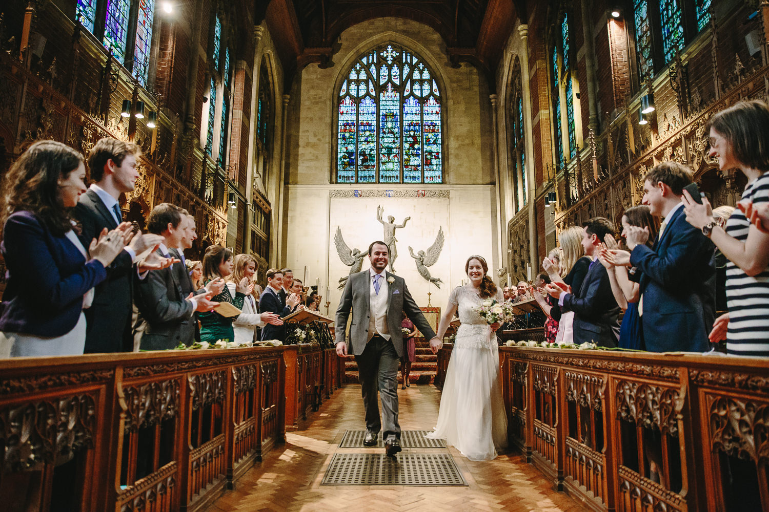 Bride and groom walking down inside Sewlyn College Cambridge University Chapel, captured by Cambridge University Wedding photographer