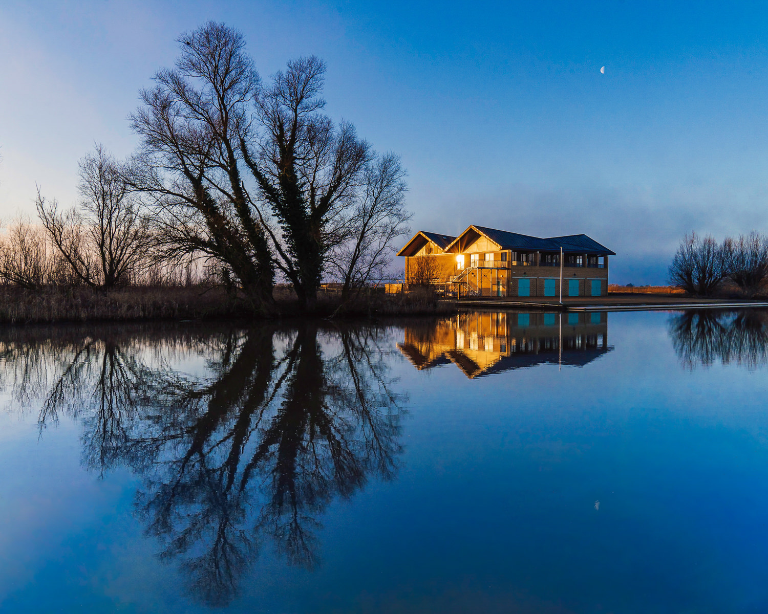 Camrbridge university boat house at sunrise on a river.